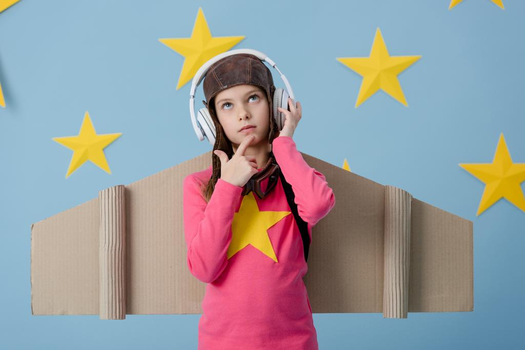 Karton düşünceli çocuk mavi yıldızlı arka planda müzik dinleme kanatlar - Fotoğraf, Görsel