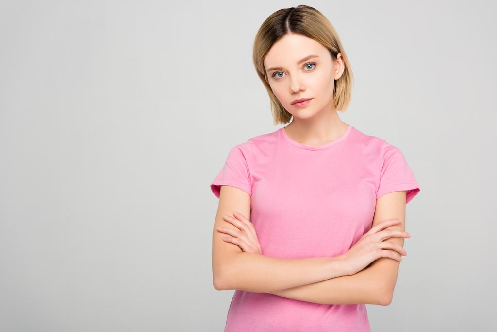 beautiful blonde woman in pink t-shirt posing with crossed arms, isolated on grey - Photo, Image