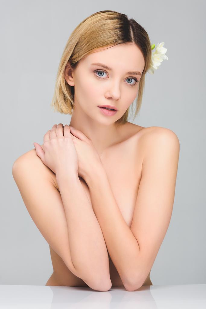 tender naked young woman with freesia flowers in hair, isolated on grey - Photo, Image