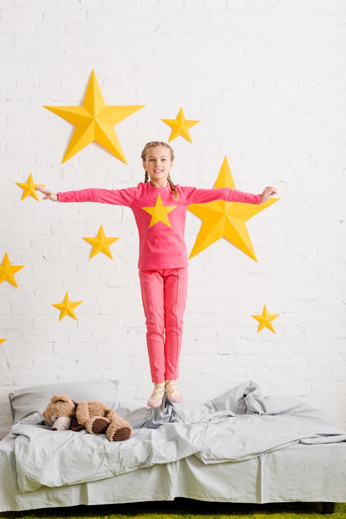 Bambino eccitato in abiti rosa che salta sul letto
 - Foto, immagini