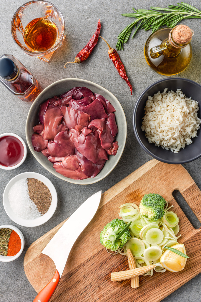 vue du dessus de viande crue, riz, épices, huile, cognac, poivrons et brocoli avec oignon sur planche à découper
  - Photo, image
