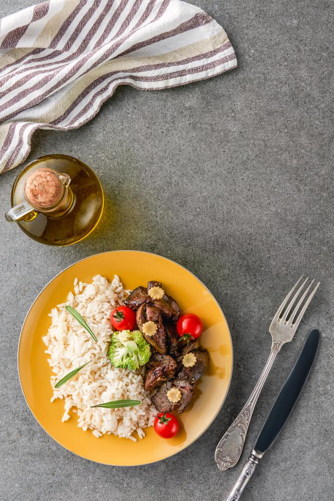 vista superior del arroz, la carne y el brócoli en el plato con aceite, tenedor y cuchillo
 - Foto, Imagen