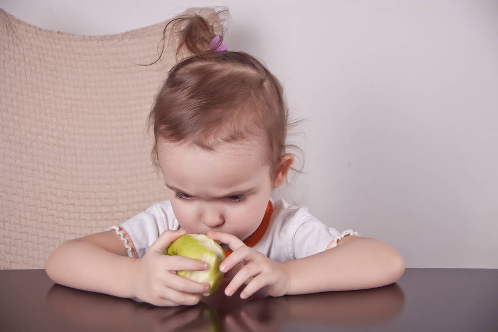 Mooi klein meisje eten een appel - Foto, afbeelding