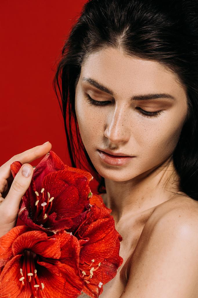 attraente tenera giovane donna con fiori di amarillide, isolata sul rosso
  - Foto, immagini