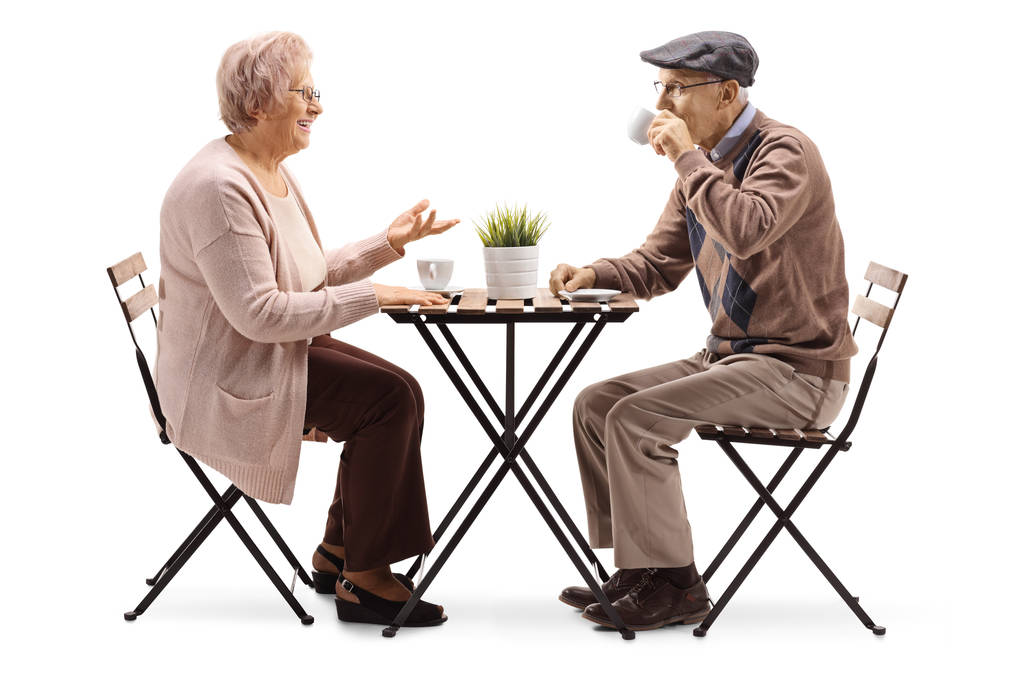 Profilbild in voller Länge von einer älteren Frau, die an einem Tisch mit Kaffee sitzt und mit einem älteren Mann auf weißem Hintergrund spricht - Foto, Bild