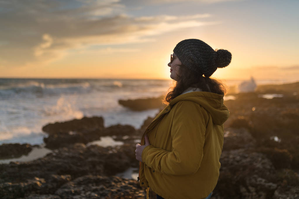 vrouw aan de zee bij zonsondergang - Foto, afbeelding