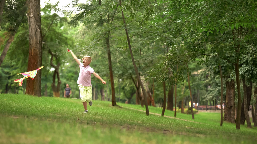 Joyeux garçon lançant cerf-volant dans le parc, activité de loisirs en plein air, enfance insouciante
 - Photo, image