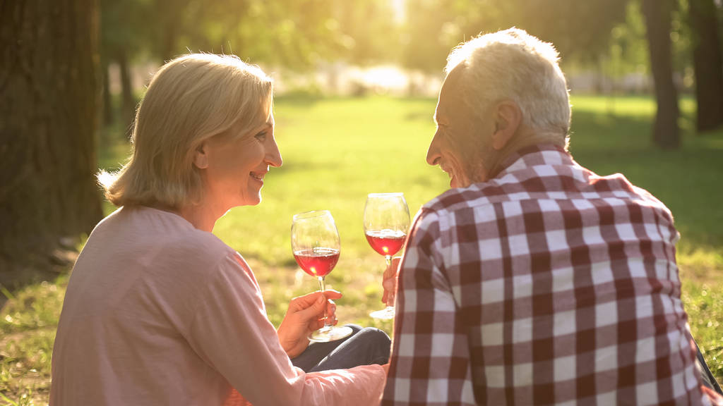 Örömteli idős pár iszik bort és évforduló parkban, dátum - Fotó, kép