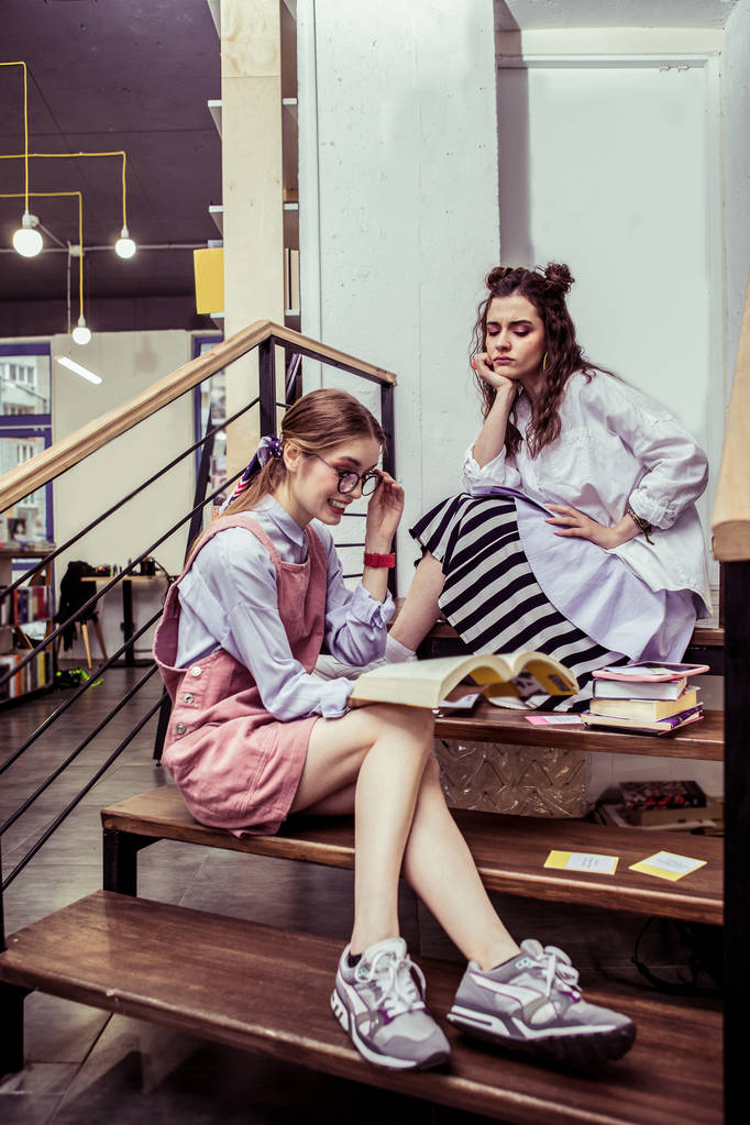 Ocupado meninas de boa aparência passar tempo em escadas de madeira na área de co-trabalho
 - Foto, Imagem