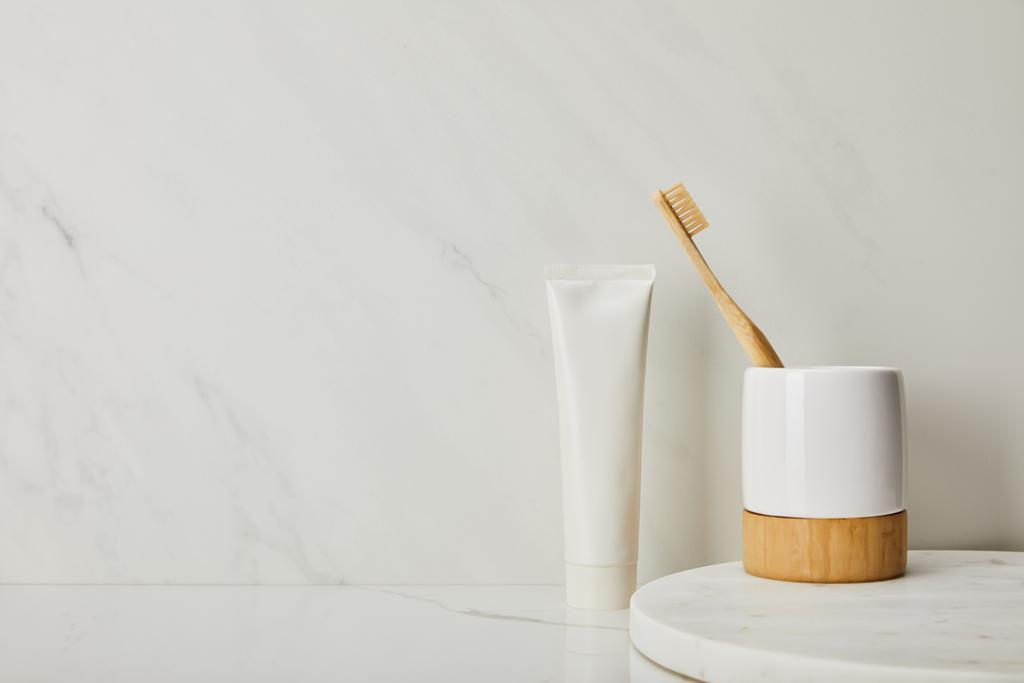 titular com escova de dentes de bambu e pasta de dentes em tubo sobre fundo de mármore branco
 - Foto, Imagem