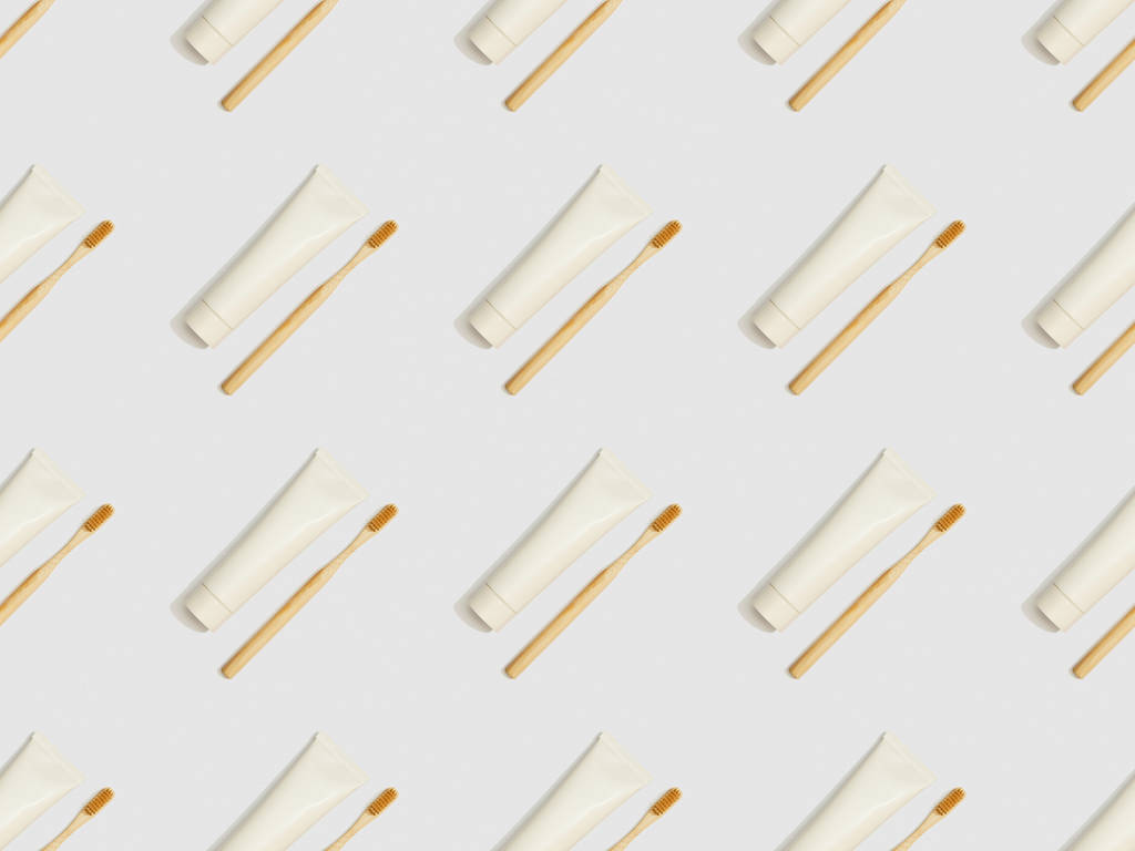 diagonally located toothbrushes and toothpaste in tubes on grey background, seamless background pattern - Photo, Image