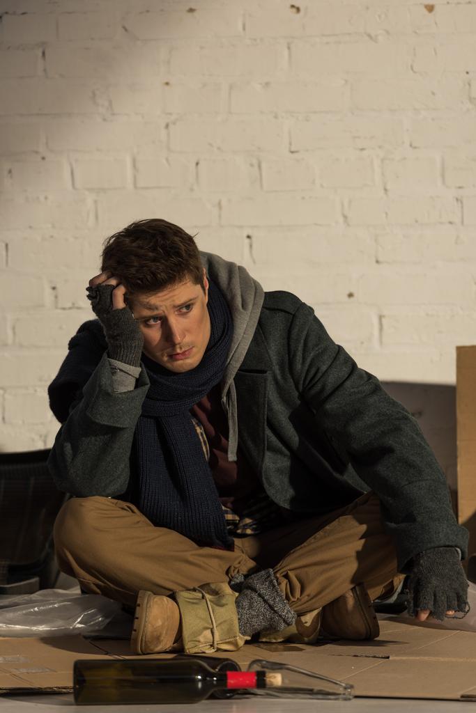 κατάθλιψη άστεγος άντρας κάθεται σε χαρτόνι και ενδυνάμωση της κεφαλής με το χέρι - Φωτογραφία, εικόνα