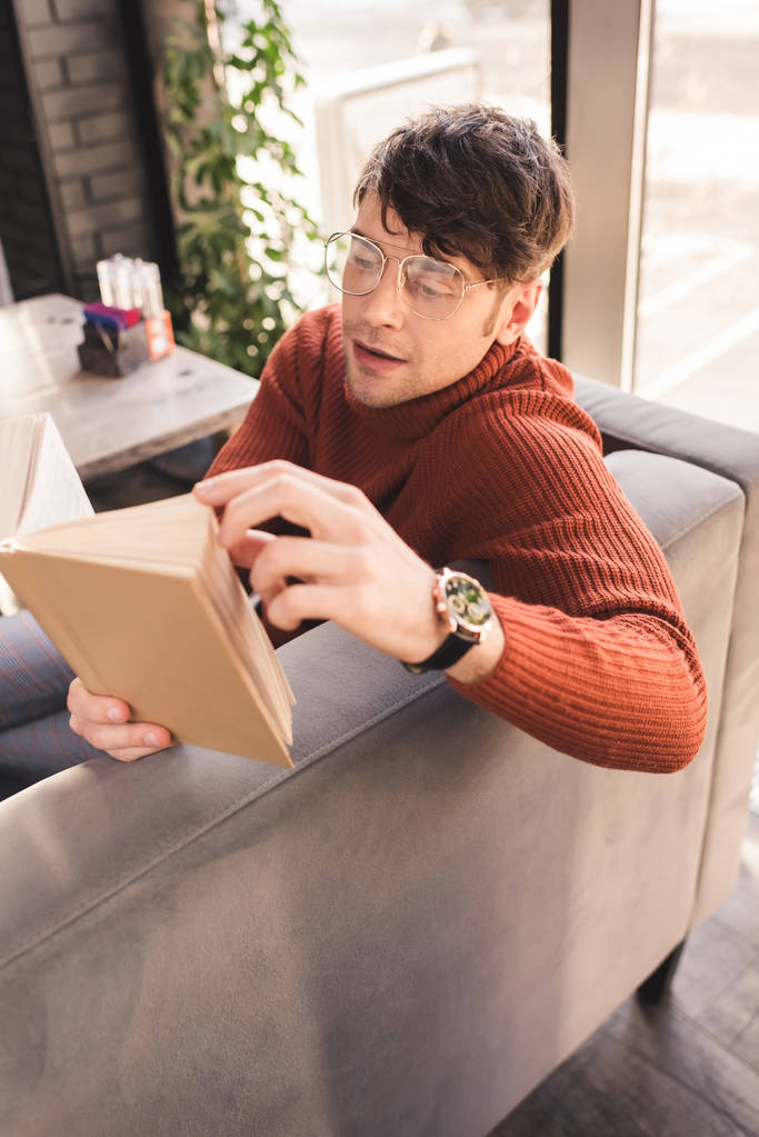 όμορφος άνδρας στο γυαλιά ανάγνωσης βιβλίου στο καφέ - Φωτογραφία, εικόνα