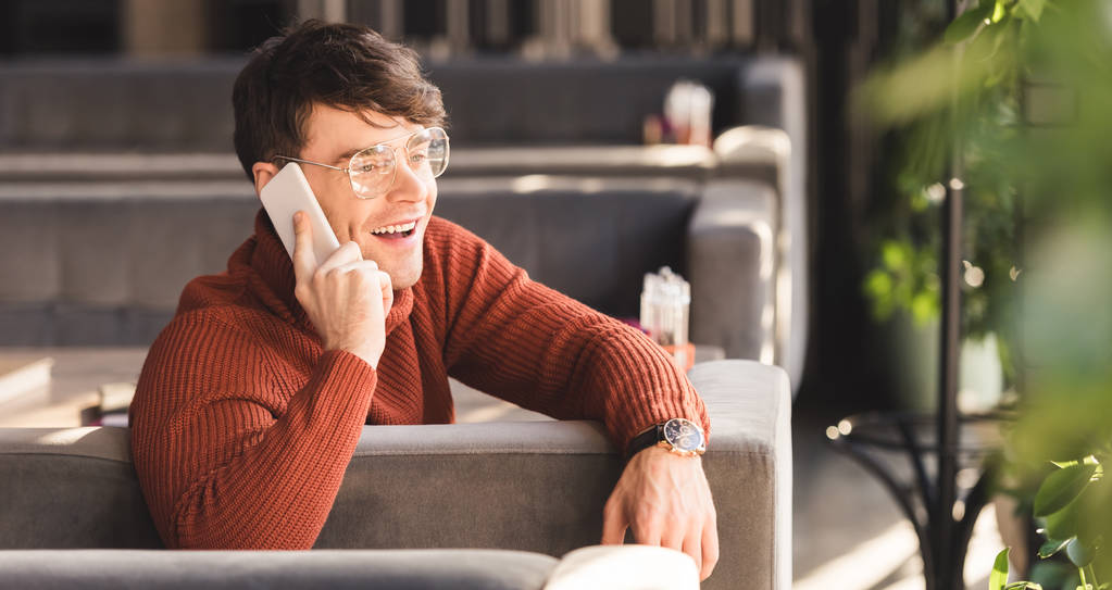 uśmiechnięty mężczyzna rozmowa na smartfonie siedząc w kawiarni - Zdjęcie, obraz