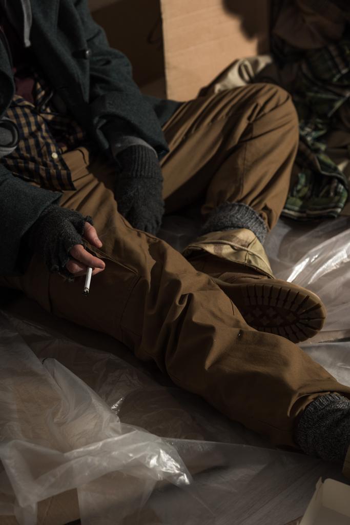 частичный взгляд на курение бездомного в перчатках без пальцев
 - Фото, изображение