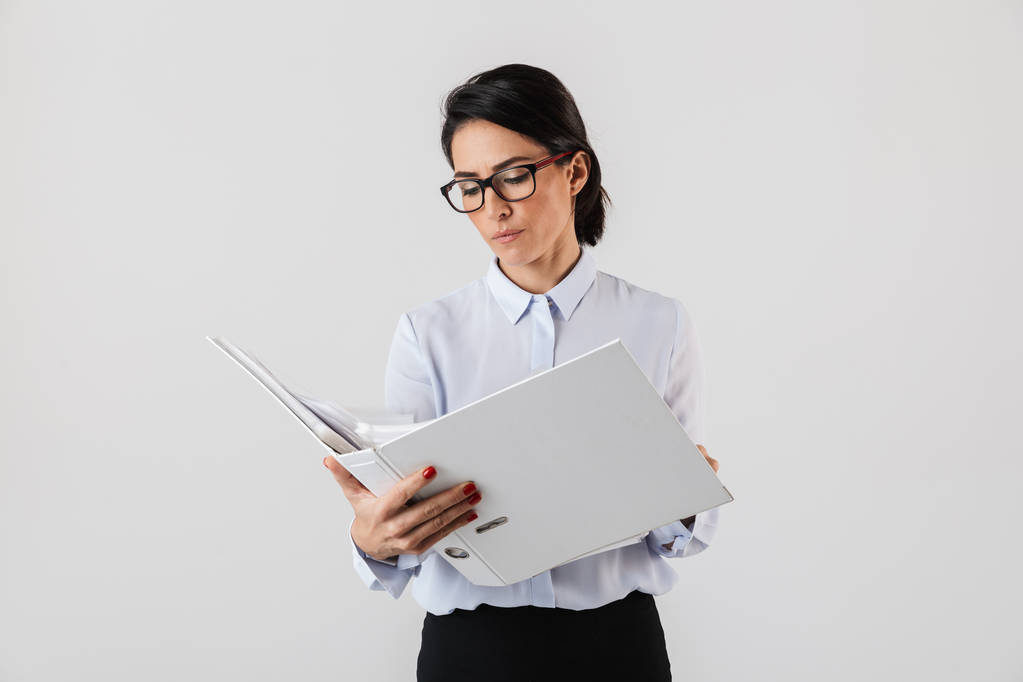 Photo of attractive female worker wearing eyeglasses holding paper folder in the office isolated over white background - Photo, Image