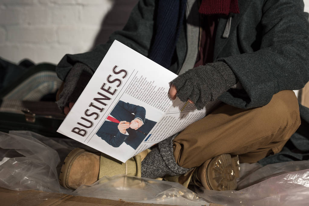 ビジネス新聞を保持している手袋指なし手袋男のビューをトリミング - 写真・画像