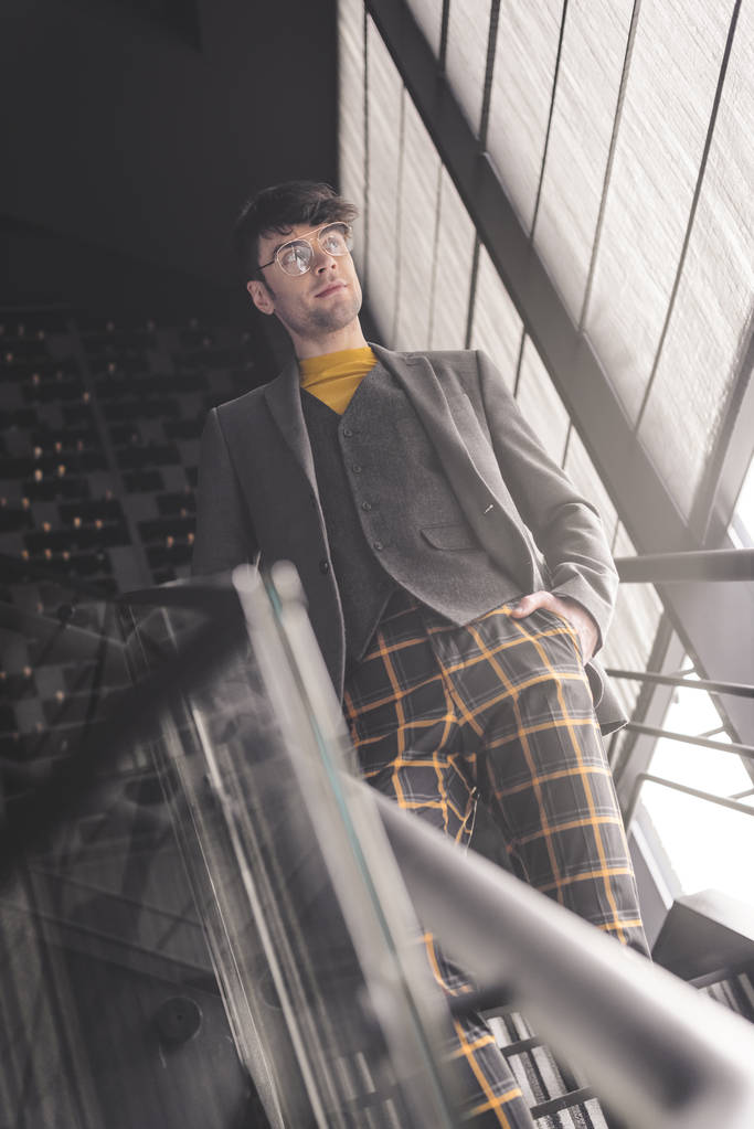 веселий стильний чоловік в окулярах стоїть з рукою в кишені на сходах
 - Фото, зображення