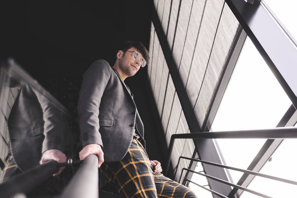 щасливий стильний чоловік в окулярах, стоячи на сходах
 - Фото, зображення