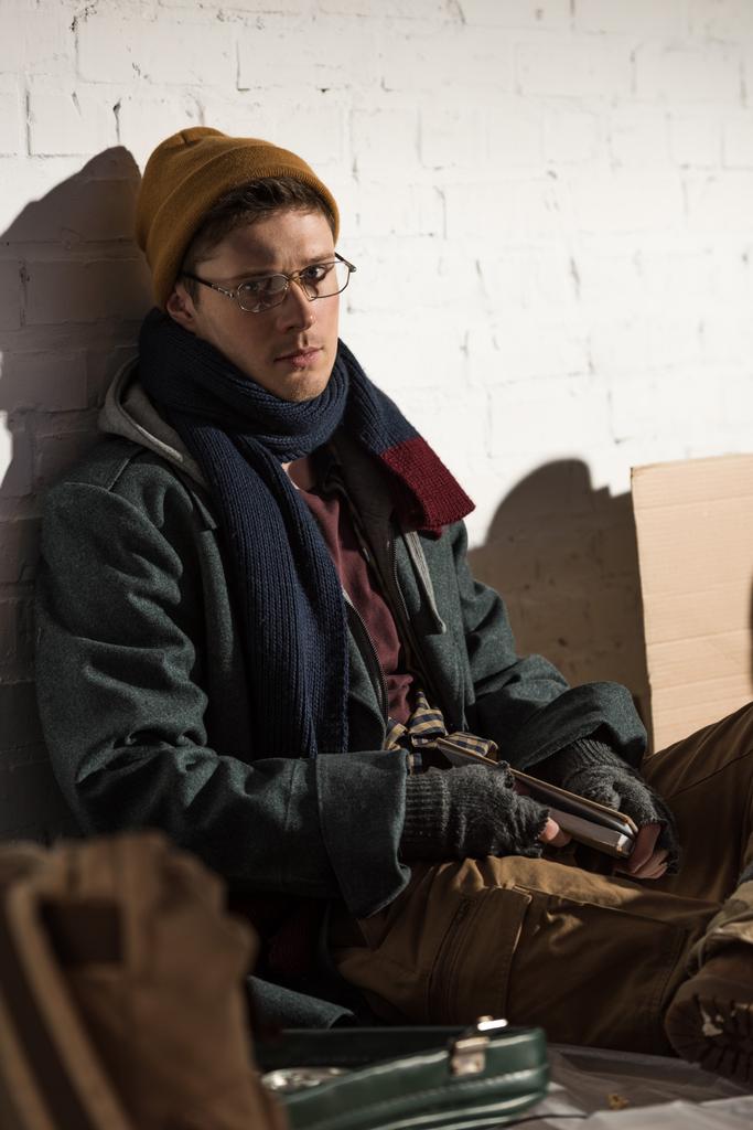 bezdomny człowiek w okularach siedzący na wysypisku śmieci - Zdjęcie, obraz