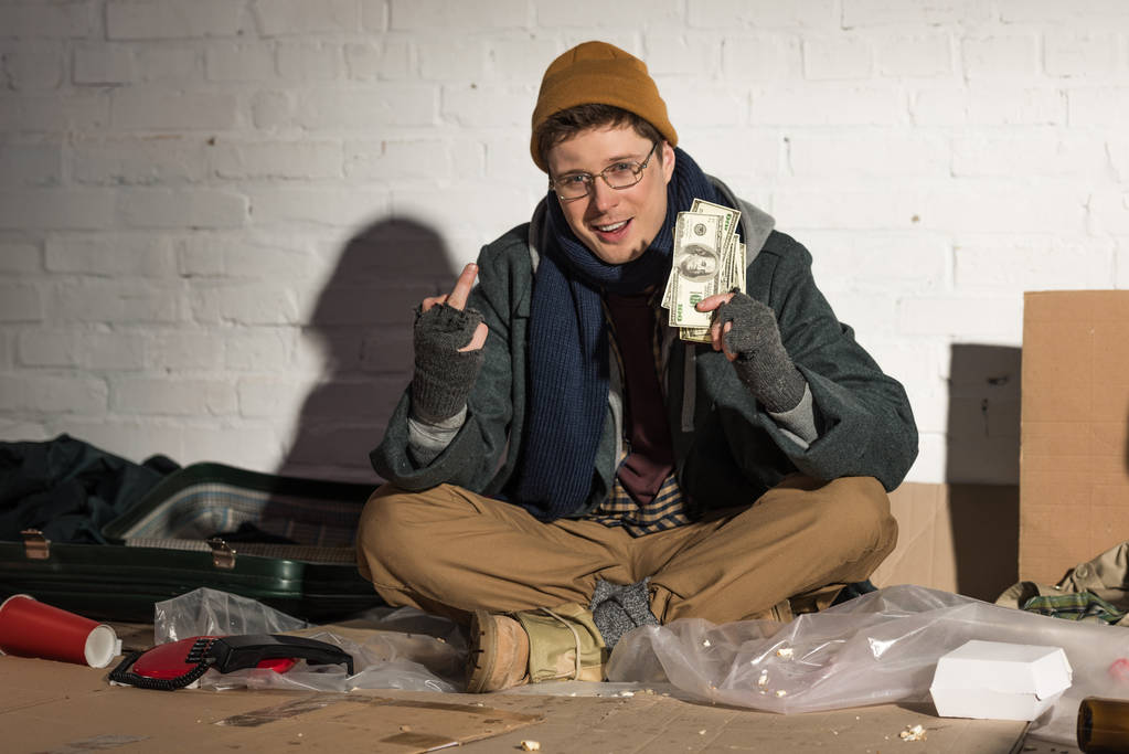 бездомний чоловік тримає гроші і показує середній палець
 - Фото, зображення