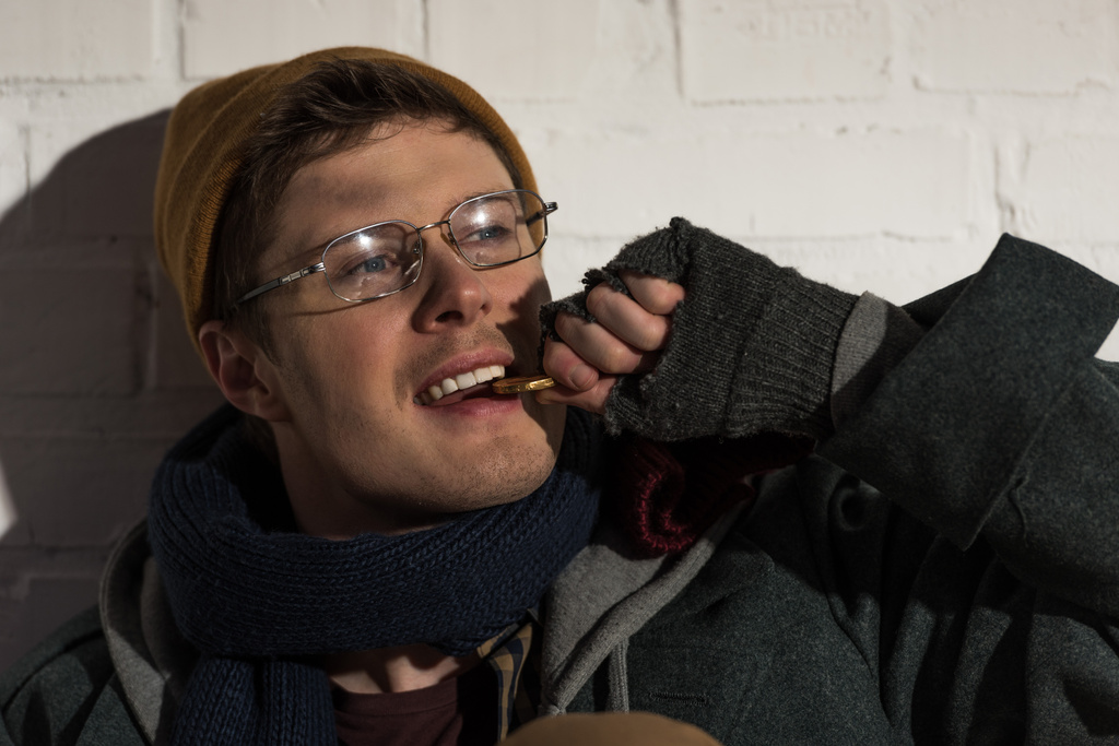 homeless beggar man in glasses checking metal coin by teeth - Photo, Image