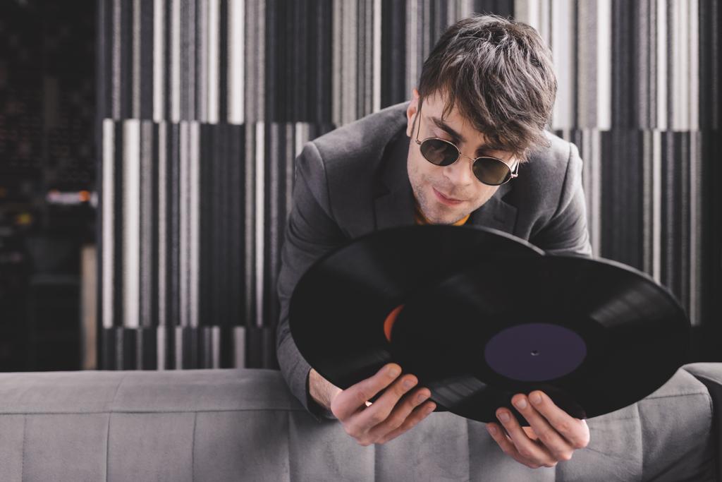 elegantní mladý muž v sluneční brýle drží retro vinylových desek - Fotografie, Obrázek
