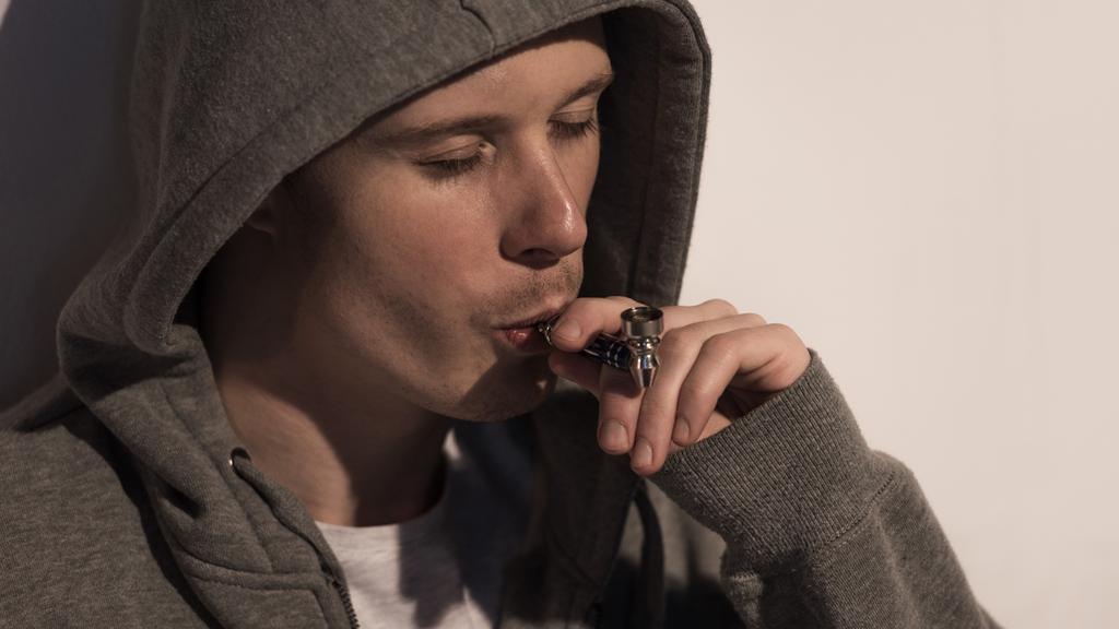 Junkie-Mann in Kapuze raucht Pfeife mit geschlossenen Augen - Foto, Bild