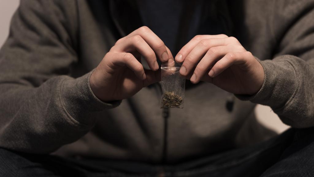 selectieve aandacht van junkie man pack opening met marihuana - Foto, afbeelding