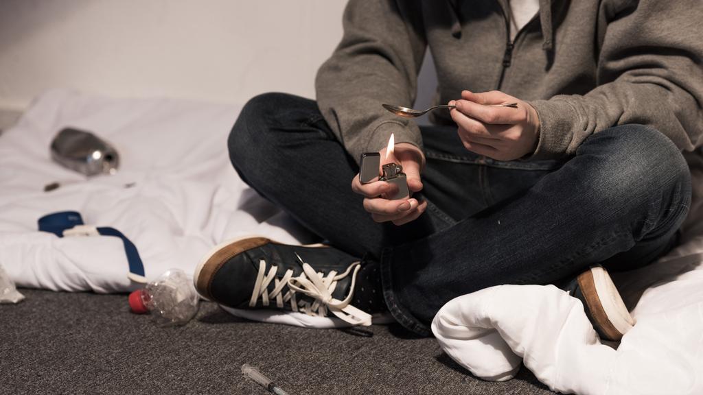 частковий вигляд наркомана, який кипить героїн у ложці на запальничці
 - Фото, зображення