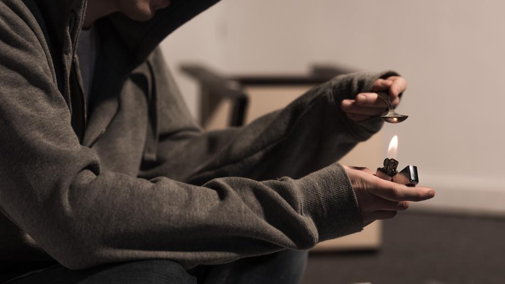 частковий вигляд наркомана чоловіка кип'ятять ложку з героїном на запальничці
 - Фото, зображення
