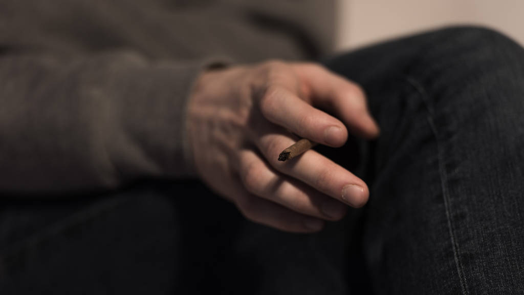selektiver Fokus der männlichen Hand mit gedrehter Marihuana-Zigarette - Foto, Bild