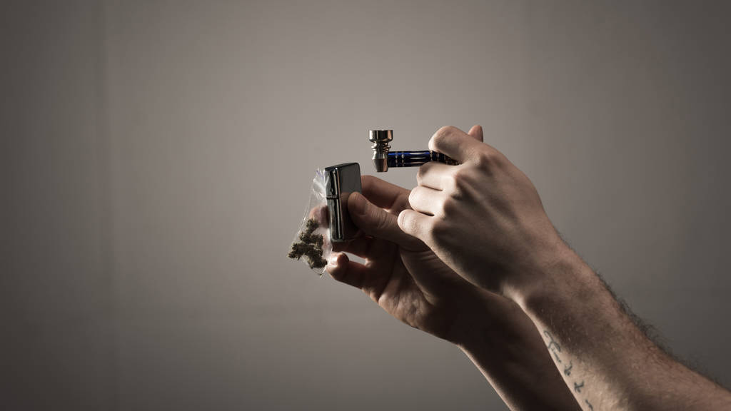 Teilansicht des Mannes mit Tätowierung mit Raucherpfeife und Feuerzeug auf grauem Hintergrund - Foto, Bild