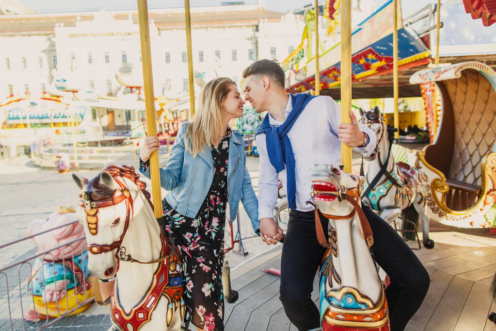 Młoda para siedzi na konie carousel i Całowanie - Zdjęcie, obraz