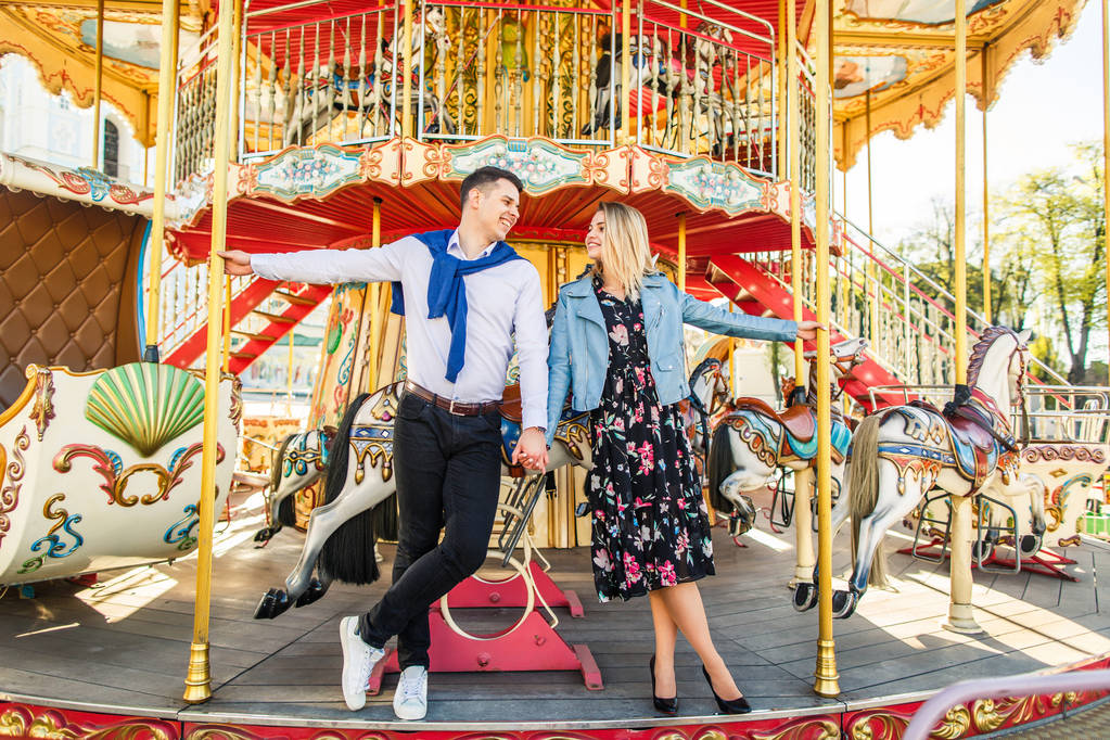 jonge gelukkige paar poseren bij carrousel - Foto, afbeelding