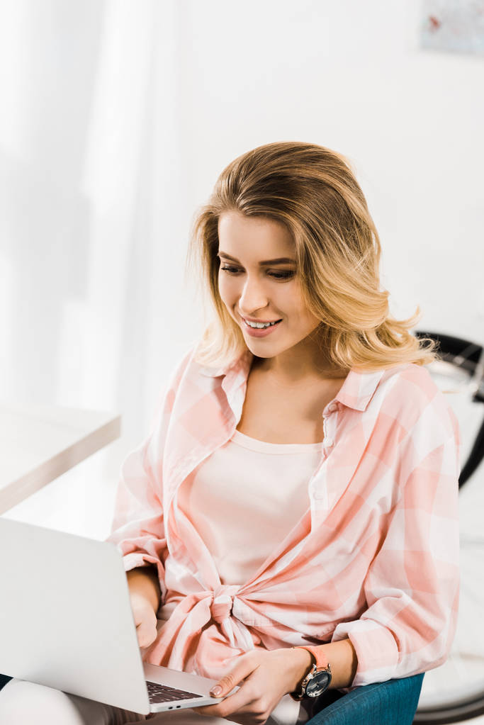 lächelnde schöne Frau im karierten Hemd mit Laptop zu Hause - Foto, Bild