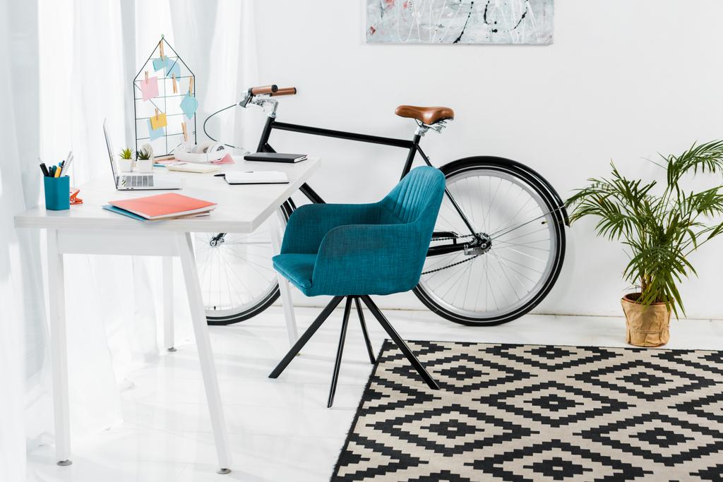 Gezellig kantoor aan huis met meubels, grote plant en fiets - Foto, afbeelding