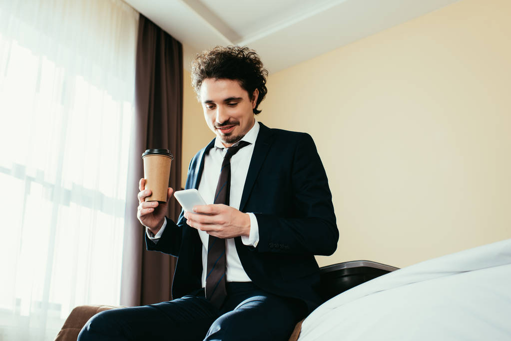 hombre de negocios feliz con el teléfono inteligente y la celebración de la taza de café desechable en la habitación de hotel
 - Foto, Imagen