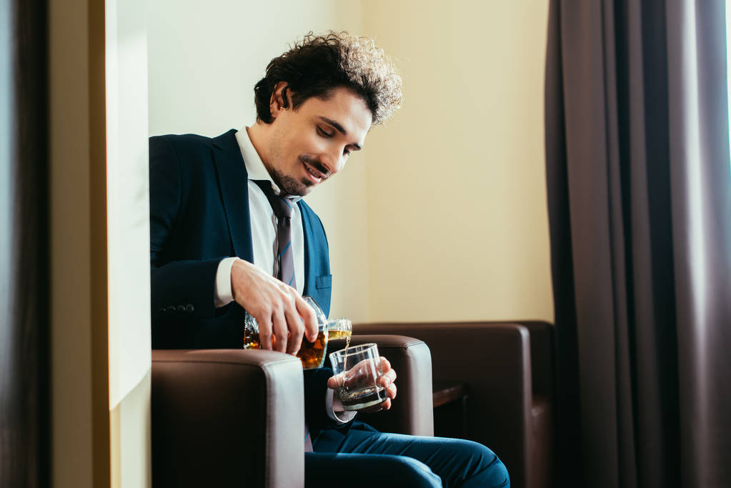 adulto hombre de negocios verter whisky en vidrio en habitación de hotel
  - Foto, Imagen