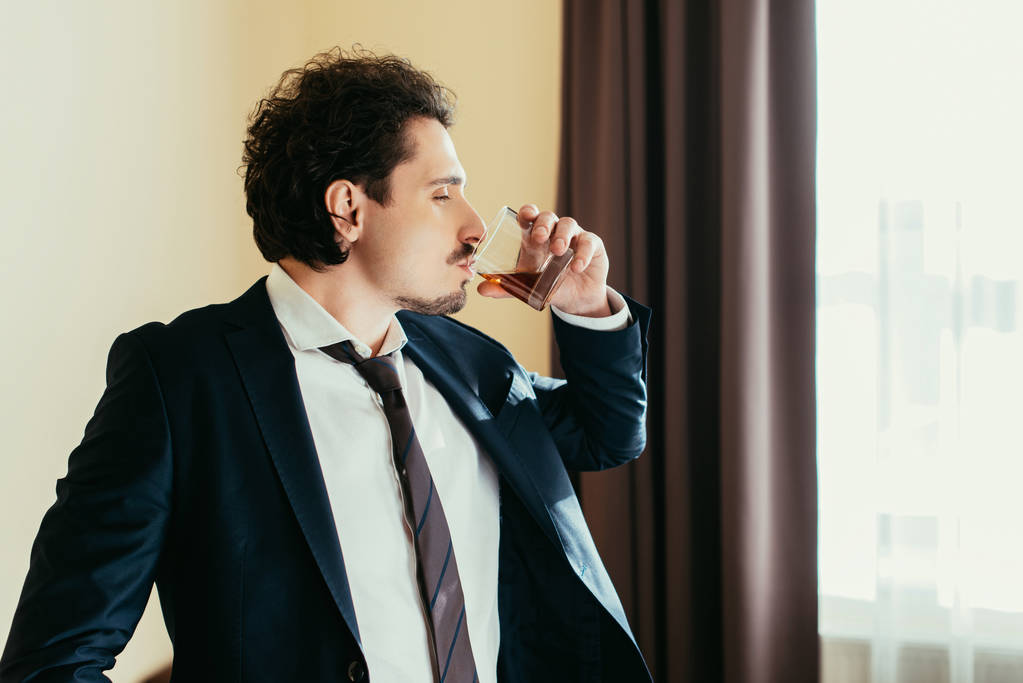 liikemies virallisessa kulumista juo viskiä lasista hotellihuoneessa
  - Valokuva, kuva