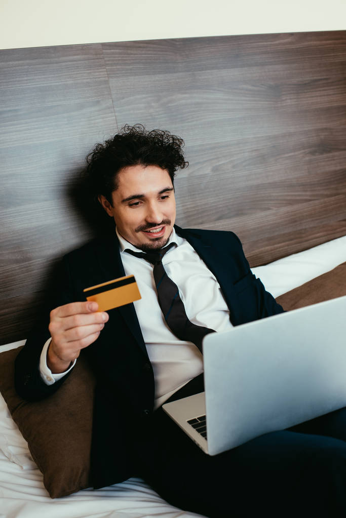 mosolygó üzletember vásárlás online hitelkártya és a laptop a szállodai szoba - Fotó, kép