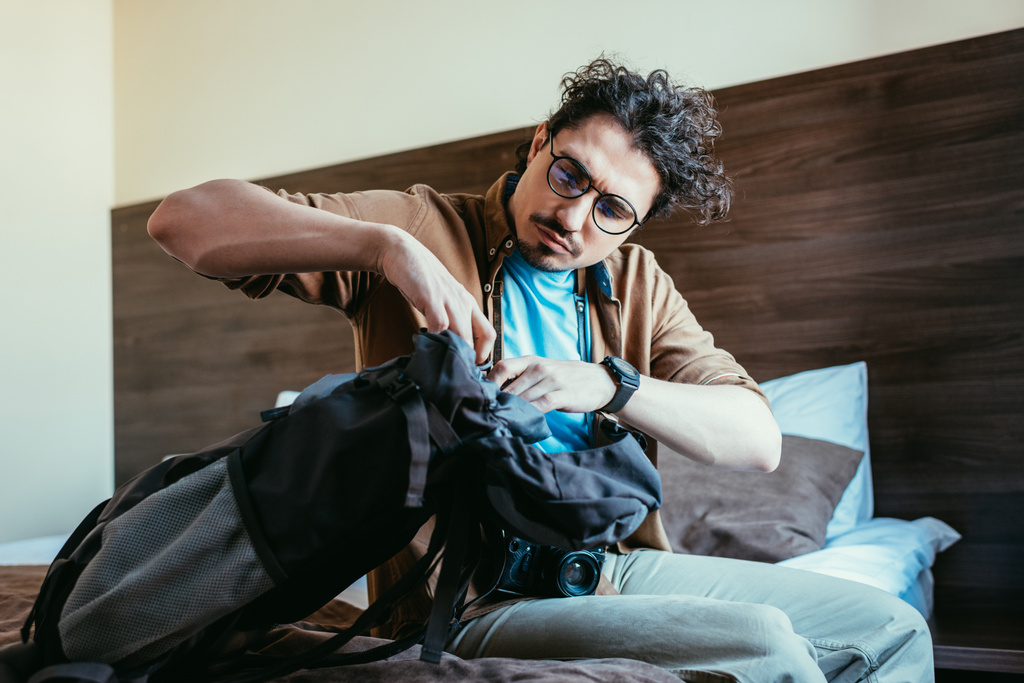 touriste masculin prenant quelque chose du sac à dos dans la chambre d'hôtel
 - Photo, image