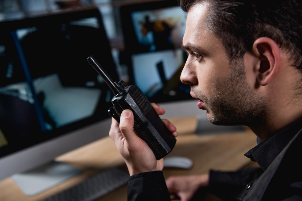 enfoque selectivo de guardia sosteniendo walkie-talkie en el espacio de trabajo
  - Foto, Imagen