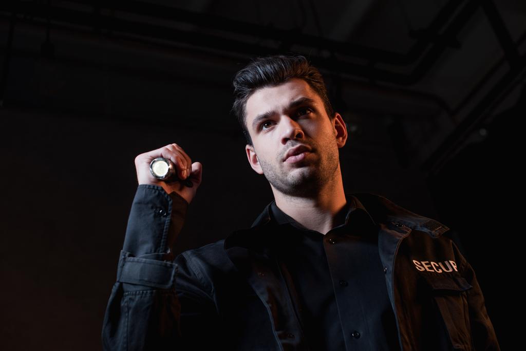 schöner Wachmann in schwarzer Uniform mit Taschenlampe  - Foto, Bild