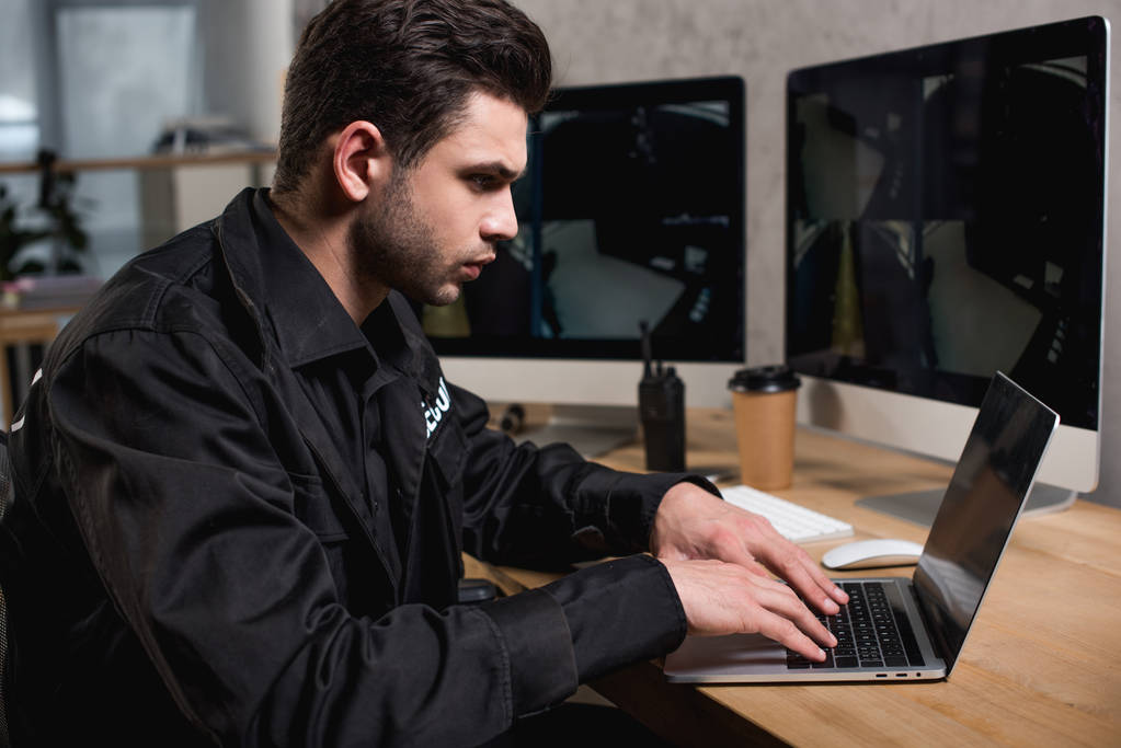 guarda pensativo em uniforme usando laptop no local de trabalho
  - Foto, Imagem