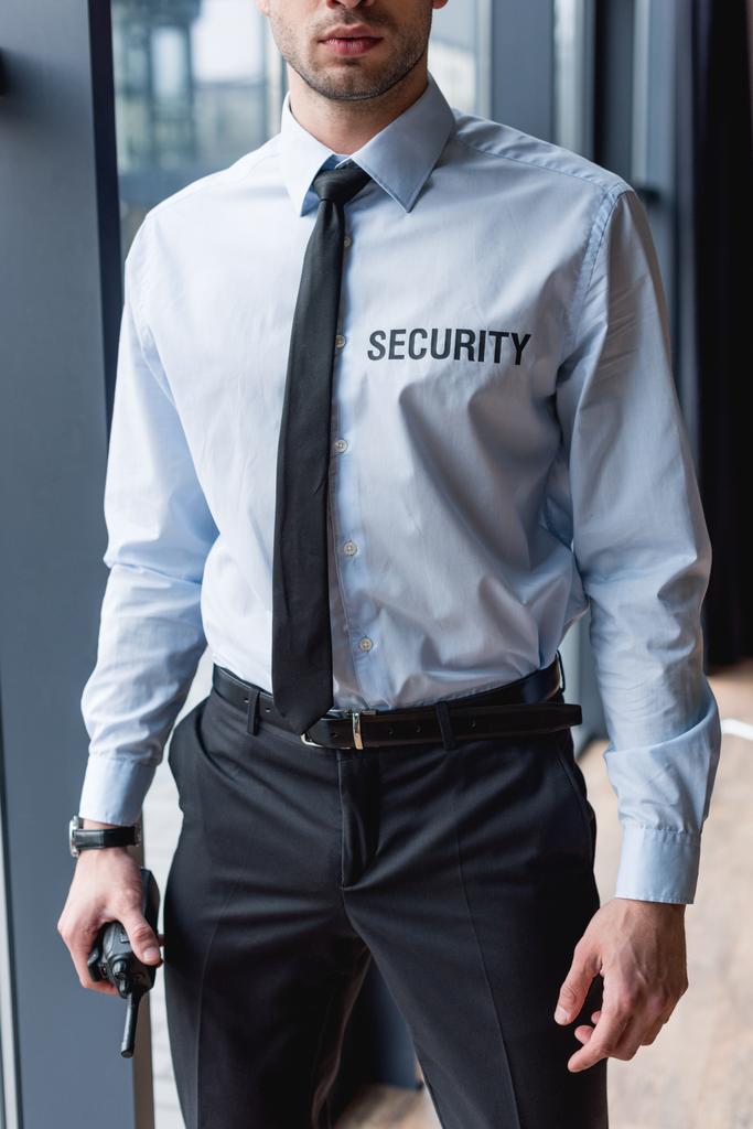 vista parcial del guapo guardia en traje sosteniendo walkie-talkie
 - Foto, Imagen
