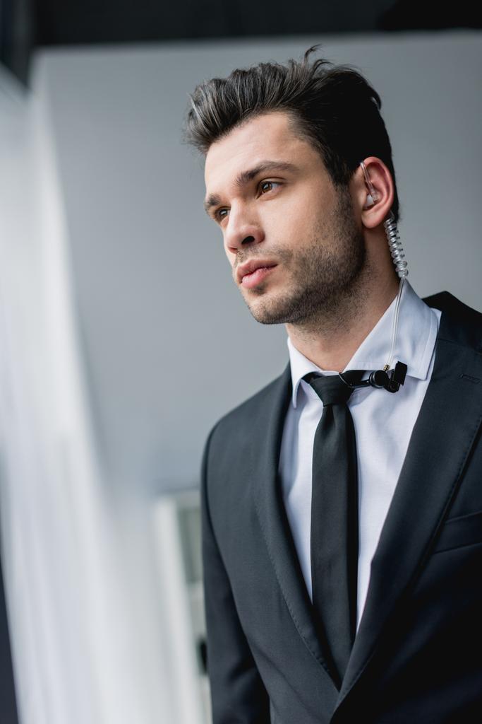 thoughtful bodyguard in suit with earphone looking away  - Photo, Image