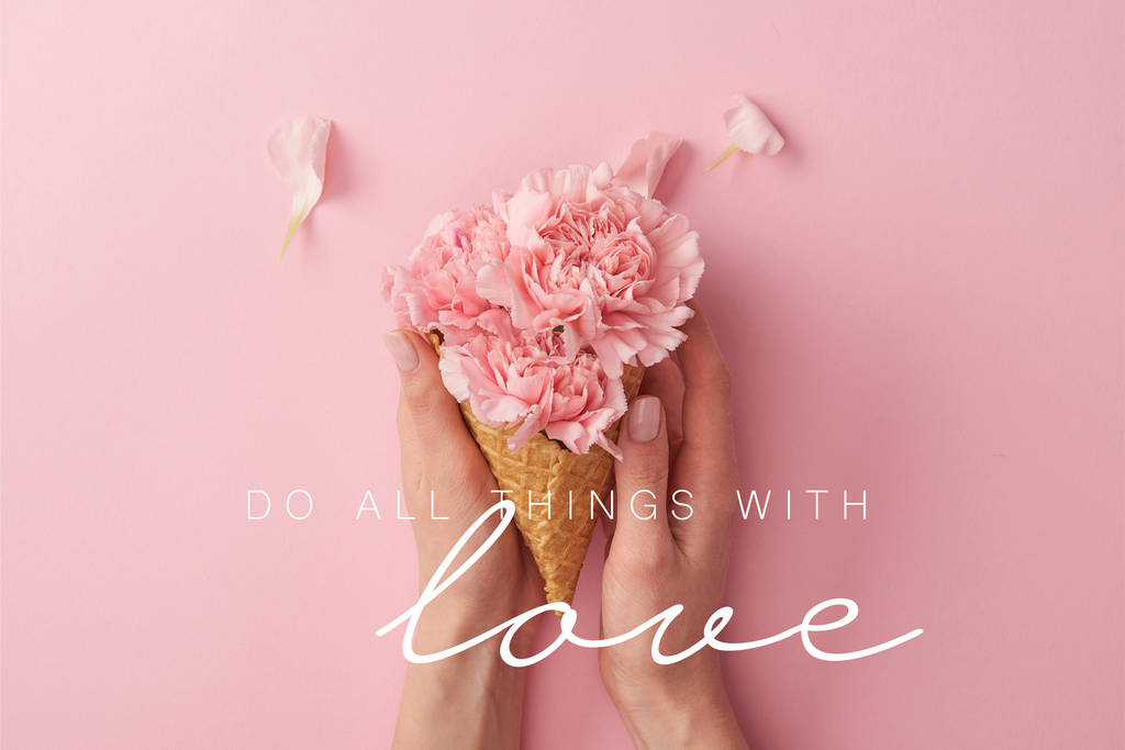 cropped view of woman holding pink carnation flowers in hands with do all things with love illustration - Photo, Image