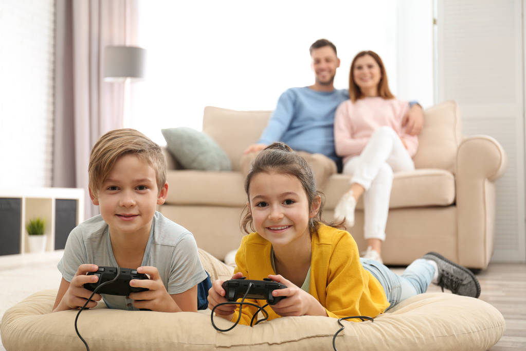 かわいい子供たちの両親が自宅のソファーで休んでいる間ビデオ ゲームをプレイ - 写真・画像