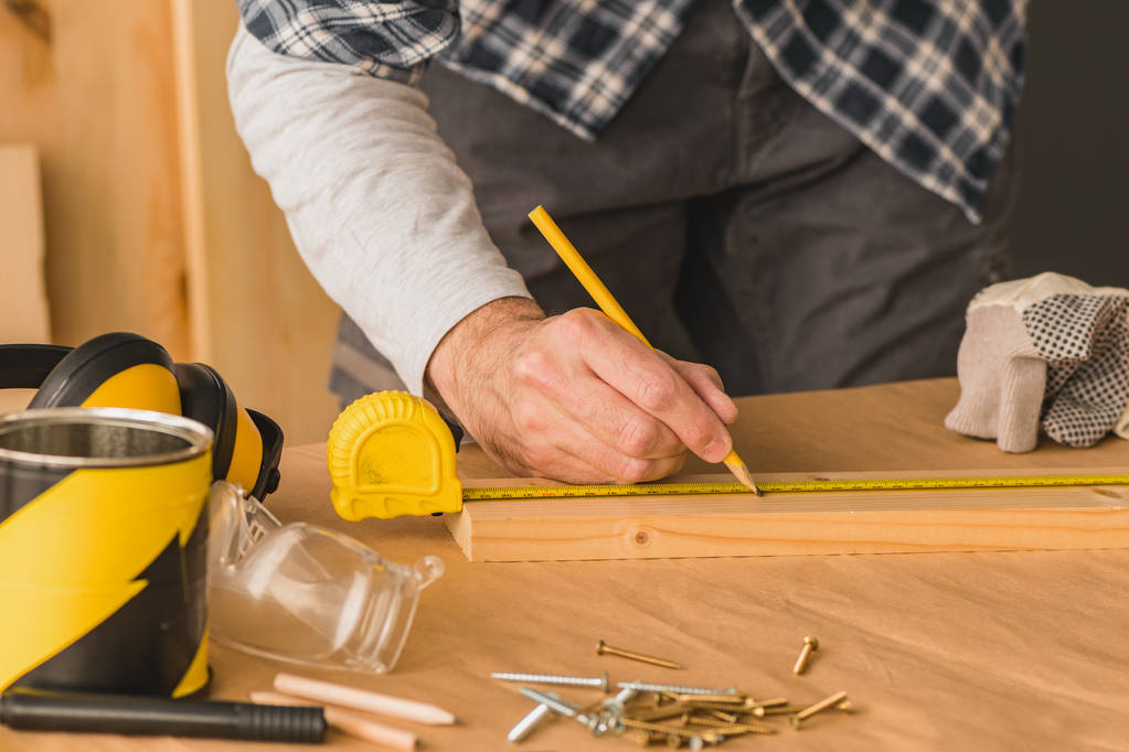 Carpintero marcando tablón de madera de pino para cortar en taller de carpintería, primer plano de las manos
 - Foto, Imagen